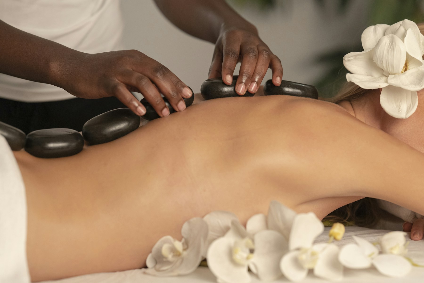 Hot-stone massage ritual with flowers in a calm spa setting